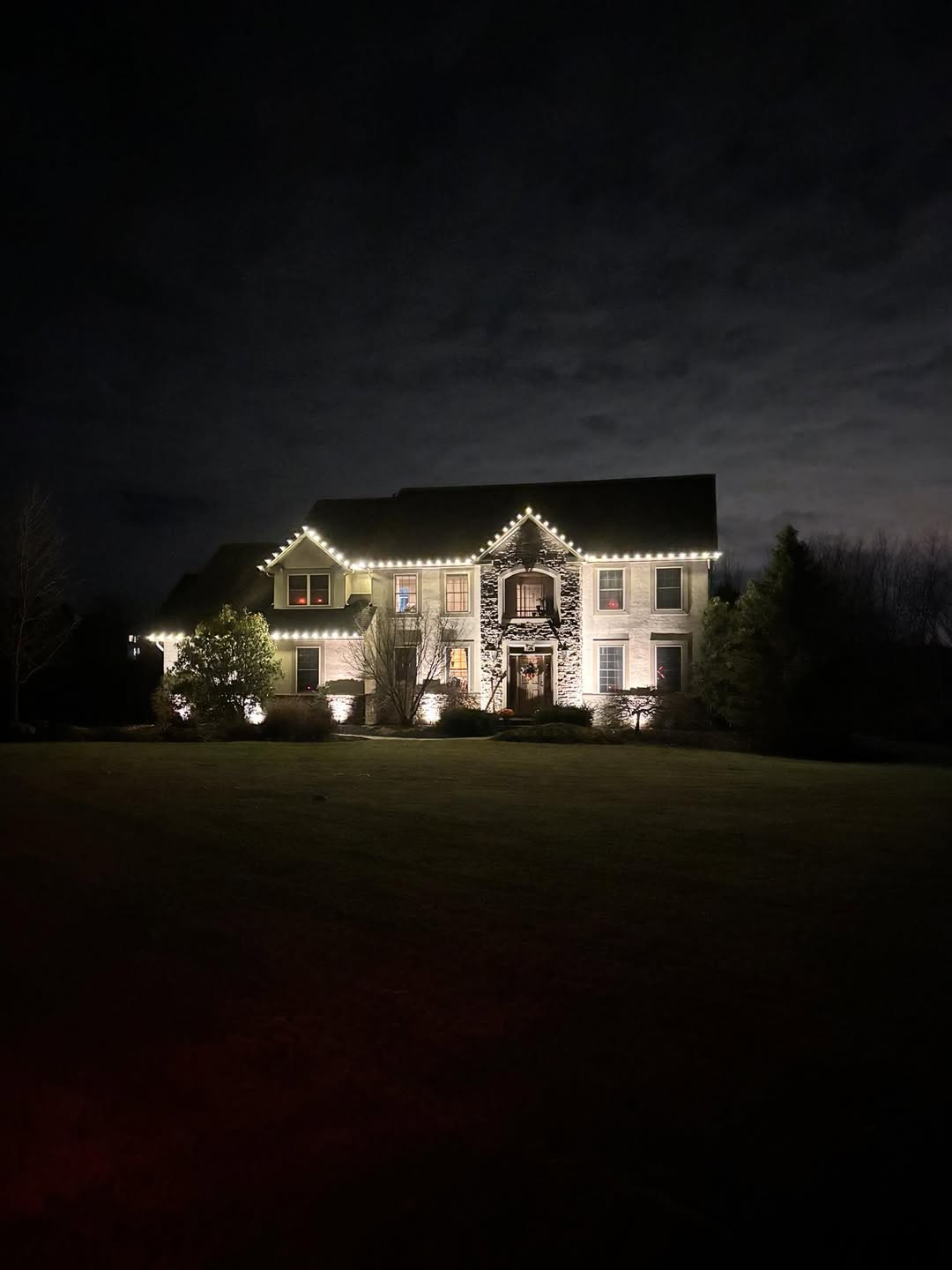 Large two-story home at night, outlined in warm white C9 roofline lighting